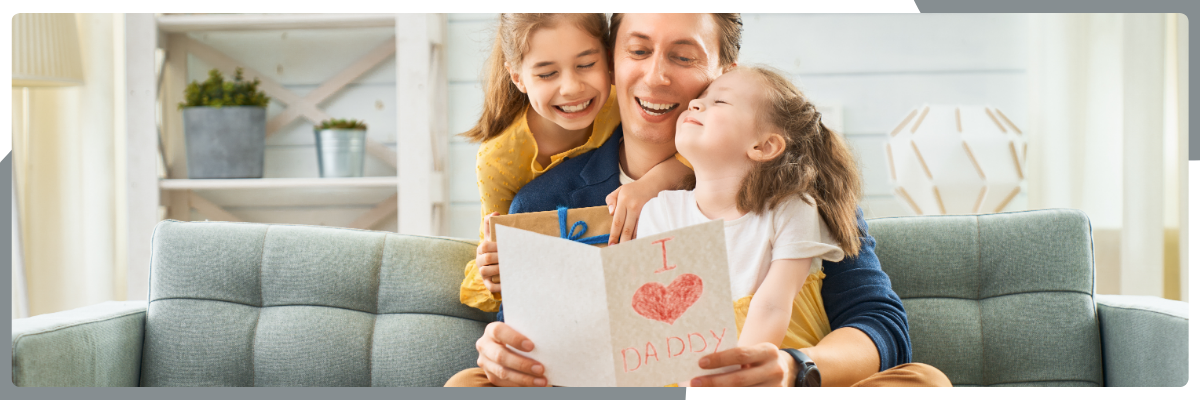 Dad reading handmade card with children at home